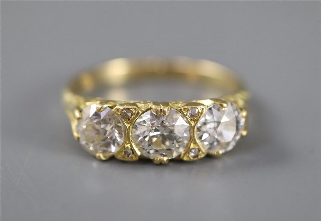 A Victorian style yellow metal and three stone diamond ring with diamond chip spacers, size Q, gross 4.5 grams.